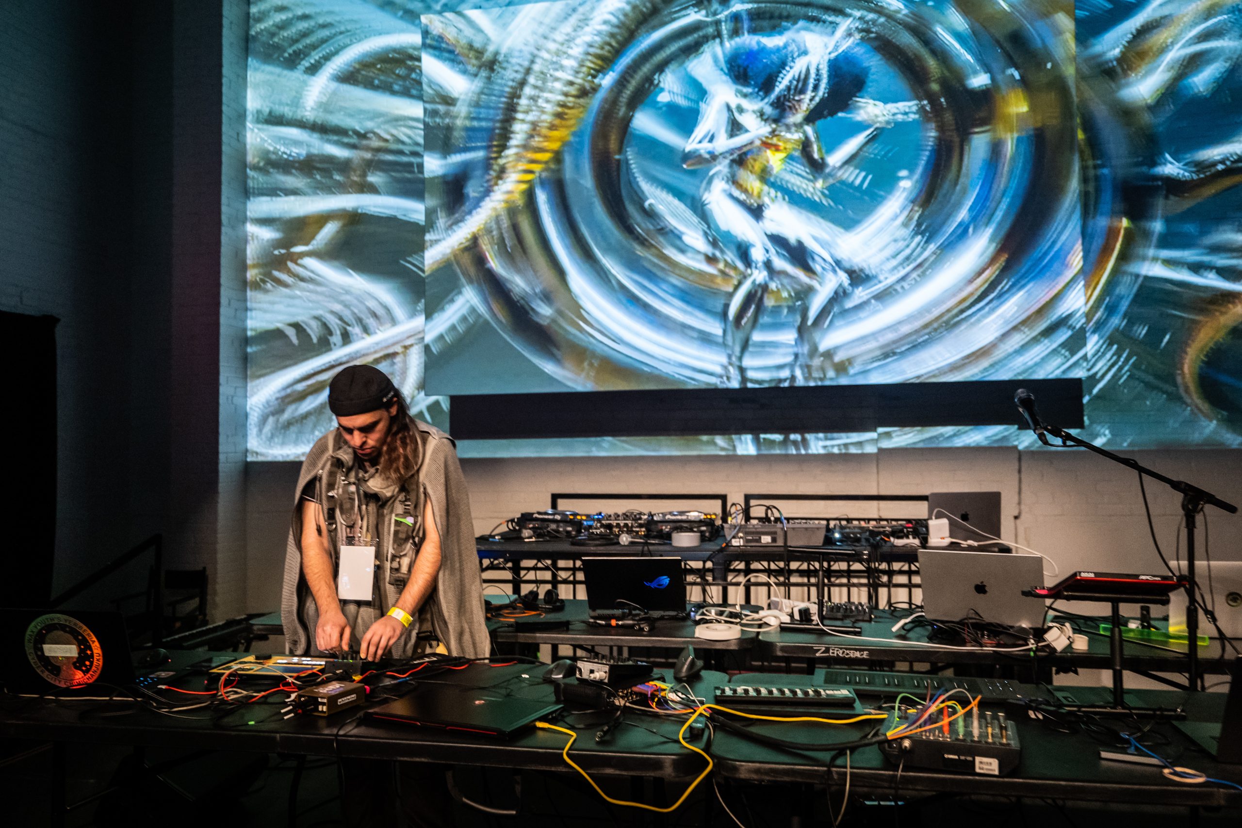 image of the glad scientist performing on stage in front of a large projection of AI videos.